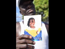 Anthony Hugh holds a picture of his dauhgter Liah Hugh, who died in a fire at her home on Giltress Street in Rollington Town, Kingston on Thursday.