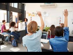Pupils raising hands in a high school science lesson.