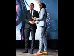 Prime Minister Andrew Holness (left) presents the Youth Award for music to Mariki Whyte.