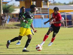 Jamaica’s Dyllan John (left) dribbles away from Trinidad & Tobago’s Malachi Webb during their under-17 international friendly at the St Elizabeth Technical High Sports Complex yesterday.
