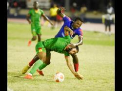 Perter McGregor (right) of Dunbeholden battles Tevoy Coldspring of Humble Lion for the ball during their Jamaica Premier League (JPL) encounter at Ashenheim Stadium last night. Humble Lion won 2-1.