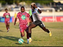 Cavalier’s Colin Anderson (right) powers past Raushan Ritch of Chapelton Maroons FC during their Jamaica Premier League (JPL) match at the Ashenheim Stadium yesterday. Anderson scored a hat-trick in Cavalier’s 4-1 win.