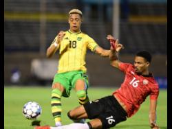 Jamaica’s Omari Hutchinson (left) is tackled by Trinidad and Tobago’s Alvin Jones during their friendly international football match at the National Stadium last night. 