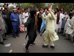 Supporters of former Prime Minister Imran Khan dance outside of the Khan house in Lahore, Pakistan, on Sunday. Police filed charges against Khan and 17 of his aides and scores of supporters, accusing them of terrorism and several other offences.