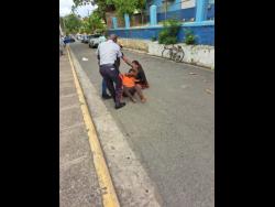 A policeman and a bystander stop a brawl between these two women outside the St Catherine Parish Court in Spanish Town on Tuesday.
