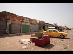 A man sits by shuttered shops in Khartoum, Sudan, on Monday. Sudan’s embattled capital has awoken to a third day of heavy fighting between the army and a powerful rival force for control of the country. 
