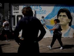 People attend a protest demanding more government social programmes near a mural of late football star Diego Maradona on the outskirts of Buenos Aires, Argentina, recently.