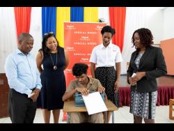 Student at the Salvation Army School for the Blind and Visually Impaired, Rohan Nelson (centre), uses a braille machine donated to the school by Digicel Foundation. Looking on (from left) are the school’s principal, Iyeke Erharuyi, Digicel Foundation’s CEO Charmaine Daniels, and senior operations manager, Jodi-Ann McFarlane, and the school’s vice-principal, Shereene Whyte. 