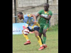Waterhouse’s Andre Fletcher (left) is bundled off the ball by Humble Lion’s Xavian Virgo during their Jamaica Premier League (JPL) football match at the Waterhouse Mini-Stadium on Sunday. The match drew 0-0.