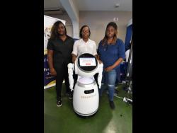 University of Technology (UTech) students (from left) Dayjaney Pringle (left), Carlishe Nicholson and Shanice Facey stand with their robot friend at the Jamaica Constabulary Force 2023 Quality and Technology Expo at the National Arena on Thursday. Facey believes the robot can be utilised by the police to handle some tasks.