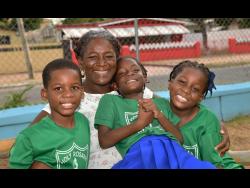 Teacher and mother of triplets, Bridget Thompson-Dunkley, lovingly embraces her children (from left) Jordan, Amanda and Amelia-Rose Dunkley.