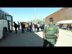 A US Border Patrol agent watches as undocumented immigrants board a bus at a checkpoint in Yuma, Arizona. 