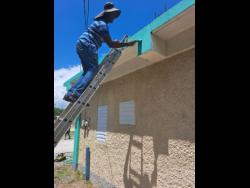 St Catherine South East Member of Parliament, Robert Miller, paints a section of the Bridgeport Infant School.