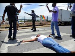 Former media executive Kay Osborne lies in the middle of the road, on a pedestrian crossing, in front of the Ministry of Finance and Public Service offices at Heroes Circle in Kingston on Monday. She was among persons participating in the daily ‘Lunch Time Protests’, which is aimed at getting the government to roll back the high salaries that have been granted to members of the political directorate.