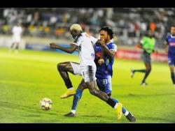 Cavalier’s Colin Anderson (left) is tackled by Mount Pleasant’s Shaquille Dyer during the Jamaica Premier League (JPL) final at Sabina Park last night. Mount Pleasant defeated Cavalier 2-1 to win their first JPL title.