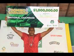 Wilfred Barnes, the champion of the inaugural Supreme Domino Masters Series, proudly displays the $1 million symbolic check, triumphantly showcasing his achievement at the highly-anticipated final on Sunday at the Chinese Benevolent Association (CBA).