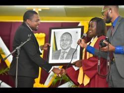 De facto information minister Robert Morgan (left) receives a pencil portrait of himself from student Garcia Young, during the Holmwood Technical High School’s graduation held at the institution in Manchester last Sunday.