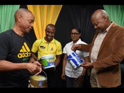 Jamaica Football Federation’s (JFF) president Michael Ricketts (right) and general secretary Dennis Chung (left) join Sherwin-Williams’ District Manager Kenneth Richardson (second left) and Lasco Home and Personal Care’s Marketing Manager Althea Pandohie to admire paints from Sherwin-Williams during a press conference to announce new sponsors of the JFF’s football programmes at the JFF offices in New Kingston on Thursday.