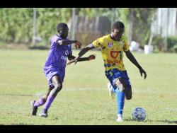 Kajay Fletcher (left) of  Kingston College tackles Kialand Smith of Hydel High during their Manning Cup match at the Royal Lakes Complex, Lime Tree Grove, Spanish Town, yesterday. Hydel won 4-0. 