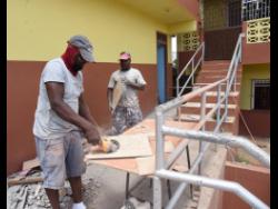 Workmen preparing bathroom facilities and ramps to facilitates students with disabilities at Alphansus Davis High School in Spaldings,  Clarendon.