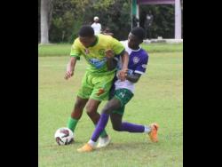 Ocho Rios High’s Joaquin Corothers (left) shields the ball from William Knibb Memorial High’s Theonjae Bennett during the ISSA/daCostaCup match at the William Knibb Sports Complex yesterday. Ocho Rios won 1-0.