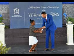 Prime Minister Andrew Holness (right), hands Shauna Adderly the keys to her new home in the Windsor Hills housing development in Trelawny on Wednesday. A total of 77 solutions were handed over under phase one of the National Housing Trust project.