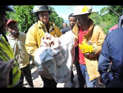 After digging through rubble of the collapsed house, firefighters emerge with the body of Timera Dennie. The infant did not survive.