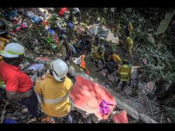 Fire personnel and residents of Bowden Hill in St Andrew dig through the collapsed building in hopes of finding Baby Timera alive.