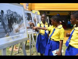 Grade-six students of Keith Primary and Infant School in St Ann look at a historic photograph displayed by the Jamaica Information Service during the 24th staging of the Seville Heritage Expo, held at the Seville Heritage Park in St Ann.