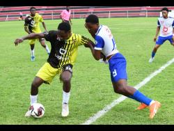 Rudolph Brown/Photographer 
Charlie Smith’s Daniel Clarke (left) keeps Hydel’s Derron Campbell at arm’s length during their ISSA/Digicel Manning Cup schoolboy football match yesterday at Anthony Spaulding Sports Complex. Hydel won 2-0.