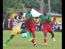 Treasure Beach’s Jay Jamerson (left) fights off a challenge from Humble Lion’s Andrew Vanzie as Afiba Chambers looks on during their opening Jamaica Premier League encounter at Effortville in Clarendon yesterday. Humble Lion won 1-0.