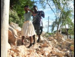 Residents walk over the rubble after a massive landslide blocked the entrance to the community of Melbrook Heights, Harbour View, St Andrew.