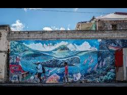 People walk past a mural of a whale created by artist Marcus Cuffi in Roseau, Dominica, on Sunday. (AP Photo/Clyde K Jno-Baptiste)