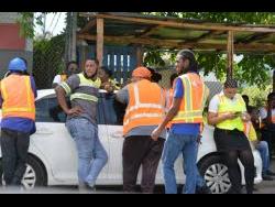 Workers gathered on the roadside moments after a bomb threat was announced at the Kingston Wharves facility on Monday.