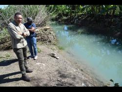 Prime Minister Andrew Holness looks at a section of the Plantain Garden River that overflowed its banks and flooded farms in Golden Grove, St Thomas. Farmerrs suffered millions of dollars in losses due to floodwaters that covered the fields for more than two days.