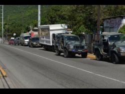 Jamaica Defence Force vehicles line the main road in Mountain View, after a joint police-military team went to the area in search of a wanted man. 