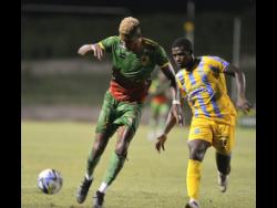 Humble Lion’s Andre Clennon (left) comes under pressure from Waterhouse’s Keithy Simpson during last night’s Jamaica Premier League game at Stadium East. Humble Lion won 1-0.
