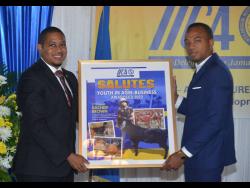 Agriculture Minister Floyd Green (left) makes a presentation to livestock farmer Kacheif Brown, who was the top awardee as the Inter-American Institute for Cooperation awarded farmers for establishing outstanding enterprises and blazing a trail in the local agriculture sector. 