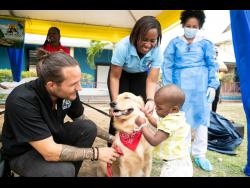 Young Leo Irving,  a patient at the Bustamante Hospital for Children, pets therapy dog Dr Teddy Barks  at the hospital. Looking on are (from left) Joey Brown, curator for the Hope Zoo;  ENT consultant Dr Marsha James;  and Nurse Yohima Barban Lao from the hospital’s Intensive Care Unit. 