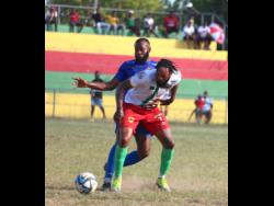 Humble Lion’s Roshane Sharpe (right) shields the ball from the ever-pressing Dunbeholden’s Fabian McCarthy during their Jamaica Premier League encounter at Effortville Community Centre in Clarendon yesterday. The game drew 0-0.