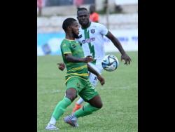 Vere United’s Kemar Beckford (left) prepares for a challenge from Tivoli Gardens’ Alton Lewis during their Jamaica Premier League match at Anthony Spaulding Sports Complex yesterday. 
Tivoli won 2-1.