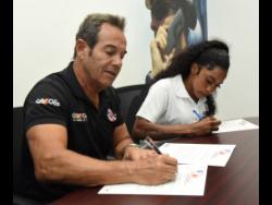 Raymond Rousseau (left), CEO, Bearings and Accessories, signs a one-year contract with female jockey Abigail Able (right) at the company’s office in downtown Kingston yesterday. Able will be a brand ambassador for the company for the next 12 months.