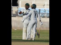 Sunil Ambris (left) congratulates Johan Jeremiah on getting to a half-century during their West Indies Championship opening round match at Sabina Park yesterday.