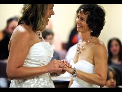 Amy Lipe (right) is all smiles as Lori Harvey slides a ring on her finger during their wedding ceremony at the Civic Centre in Evansville, Indiana on Friday, June 26, 2015. 