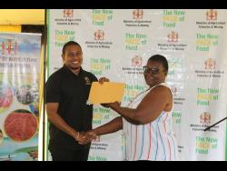 Minister of Agriculture, Fisheries and Mining Floyd Green presents a resident of the Gravel Hill Land Settlement in Wakefield, Trelawny, with her letter of possession last Tuesday.