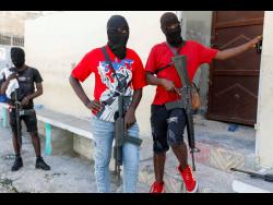 Masked members of ‘G9 and Family’ gang stand guard during a press conference by their leader, Barbecue, in the Delmas 6 neighbourhood in Port-au-Prince, Haiti on Tuesday. Haiti’s latest violence began with a direct challenge from Barbecue, a former elite police officer, who said he would target government ministers to prevent the prime minister’s return and force his resignation. 