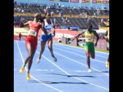 Natrece  East (left) of Wolmer's Girls' School eases after securing victory over her rivals in the Class Three girls' 200 metres at the ISSA/GraceKennedy Boys and Girls' Athletics Championships at the National Stadium today. East clocked 24.29 seconds for the victory.