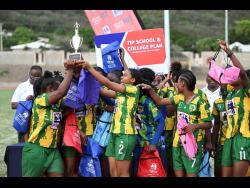 Excelsior High’s players celebrate with the championship trophy after defeating Holmwood Technical High 9-1 in the ISSA/Tip Friendly Society schoolgirls football final at the Stadium East field yesterday.