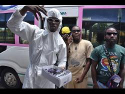 Dancehall artiste Pyneer (left) gives sunglasses to fans in Half-Way Tree.