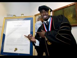Entertainer Sean Combs poses next to his honorary degree of Doctor of Humanities during the graduation ceremony at Howard University in 2014.
